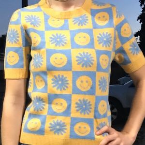 A baby blue and yellow smiley face and flower sweater shirt